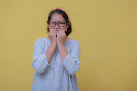 A middle-aged woman biting her nails; nervous expression.