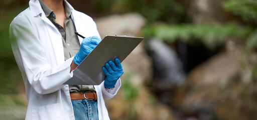 Clipboard, nature and scientist in agriculture research, sustainability and plants checklist for climate change test. Green, sustainable growth and science woman or medical person hands writing notes
