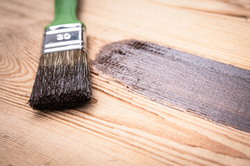 Brush with brown paint on a wooden texture background. Renovation and construction