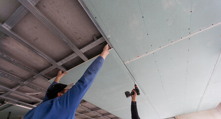 Drywall Installers. Men holding a gypsum board figured cut