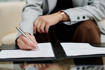 Close-up of businesswoman signing a contract at table during business meeting