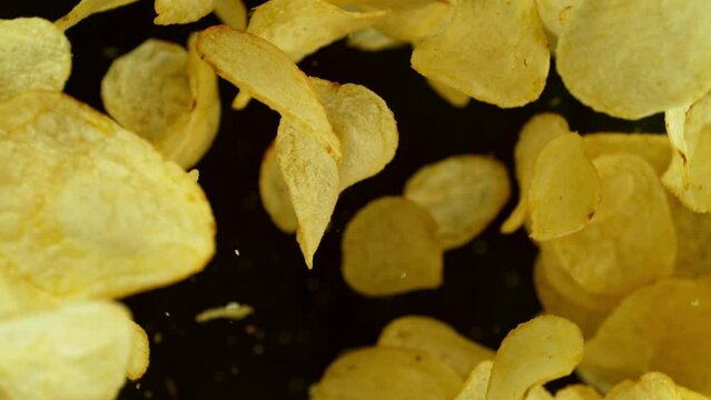 Super slow motion of flying fried potatoes chips on black background. Filmed on high speed cinema camera, 1000 fps. Camera placed on high speed cine bot, tracking the target.