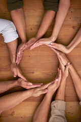 Hands, teamwork and circle with business people on a wooden table in the office closeup from above....