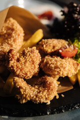 Fried shrimp in breadcrumbs served in food paper on plate