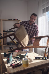 Man working in a small home workshop for furniture repairing and restoration.