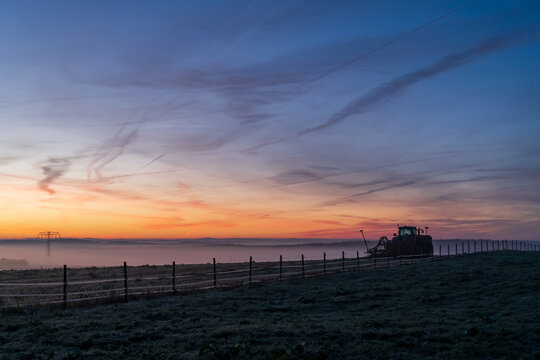 Traktor vor eisigem Sonnenaufgang