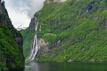 Beautiful landscape with snowy mountain peaks and waterfalls in Geiranger fjord, Norway