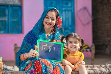 Indian rural woman with her little daughter showing chalk slate. Shiksha word in marathi...