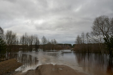 Flooded dirt road by spring floods. A flooded bridge overflowing the banks of the river.