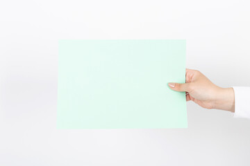 an anonymous woman's hand holds a pastel green paper. Space for message