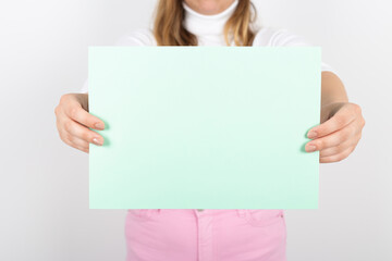 Naklejka premium anonymous woman holding a light green paper in her hands. Advertising space