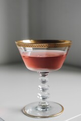 rose wine in vintage gold-rimmed champagne coupe glass
