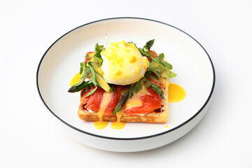 Poached egg and salted salmon on a Viennese waffle. Fresh Viennese waffle.Arugula and tomatoes. The concept of a healthy breakfast.White background.Copy space. Isolated object.