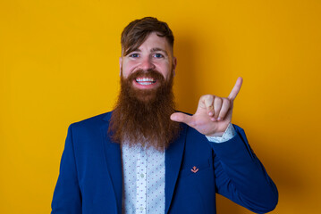 Red haired man wearing blue suit over yellow studio background showing up number six Liu with fingers gesture in sign Chinese language © Roquillo