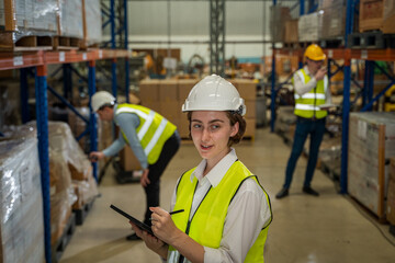 Warehouse employees reading a clipboard in a logistics centre,Warehouse worker taking packages for shipment in a large distribution centre.