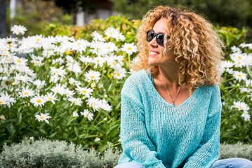 Vacation spring time season people concept lifestyle. Happy young woman smile and have outdoors leisure activity alone at the park with blossom daisy flowers in green natural background. Curly hair - Powered by Adobe