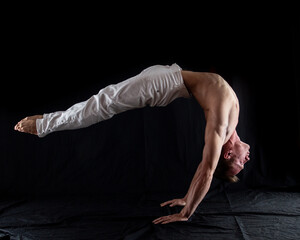 flexible circus artist keep balance on hands on a black background. concept of contortion and...