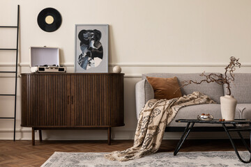 Warm composition of living room interior with mock up poster frame, wooden sideboard, gray sofa, plaid, brown pillow, gramophone, wall with stucco and personal accessories. Home decor. Template.