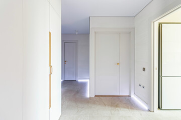 Modern entrance hall in light colors with interior doors in white and gold