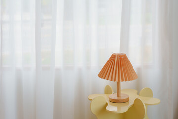 Wooden lamp on cute yellow table with white curtain background with copy space.