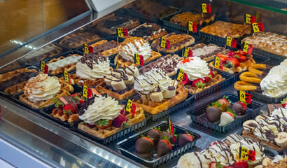 Variety of flavors and colors of rich waffles in a pastry shop, traditional food in Belgium
