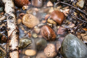 Long exposure shot of colorful rocks under the water of the small cascade