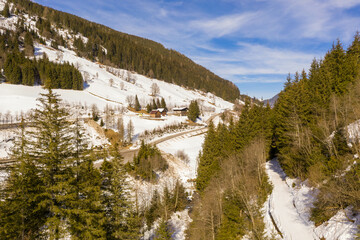 Drone photography of mountains, forest, road during winter sunny day.