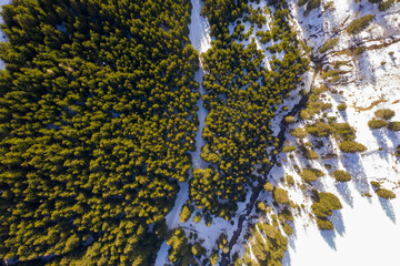 Drone photography of sky slope, forest, river, mountain and shadows during winter sunny day.
