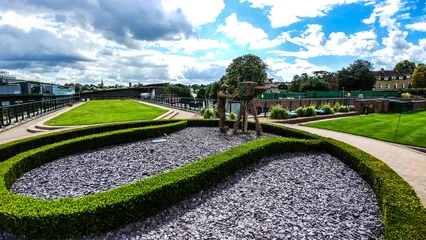 Papier Peint photo autocollant Monument historique Lush green modern garden with statues under blue cloudy sky