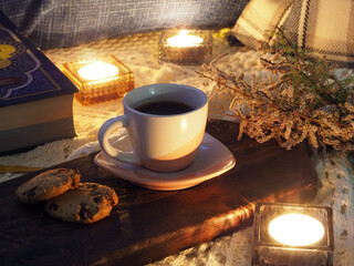 Coffee with cookies, a book, lit candles, a knitted shawl, an old wooden tray