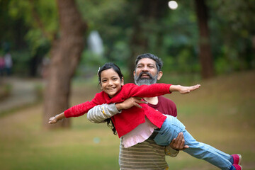 Fototapeta premium Indian man playing with his daughter at park