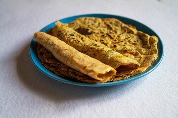 Indian inspired lentil crepe served on a blue plate, close-up