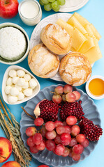 Jewish Shavuot Holiday Card. Dairy Products, Grapes, Cheese, Bread, Milk on Blue Background.