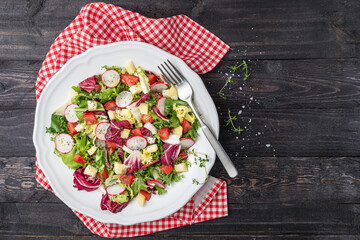 Fresh salad with mixed greens radish cheese and tomato in a plate on wooden background. Italian Mediterranean or Greek cuisine. Vegetarian vegan food.