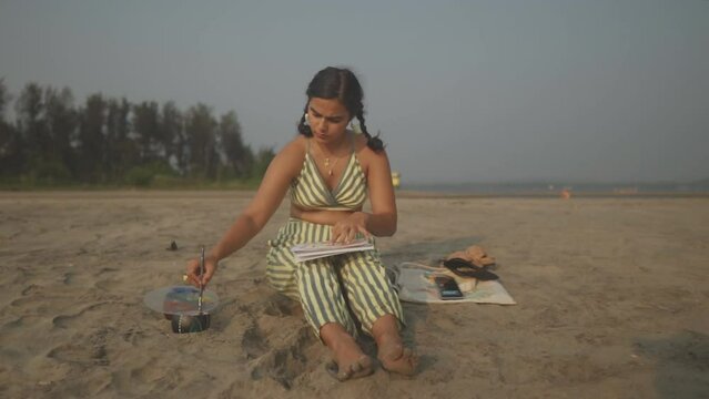 Beautiful Indian Woman Enjoys Painting Art on Her Lap Seated at the Beach