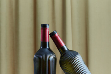 Two empty wine bottles against a backdrop of draped curtains