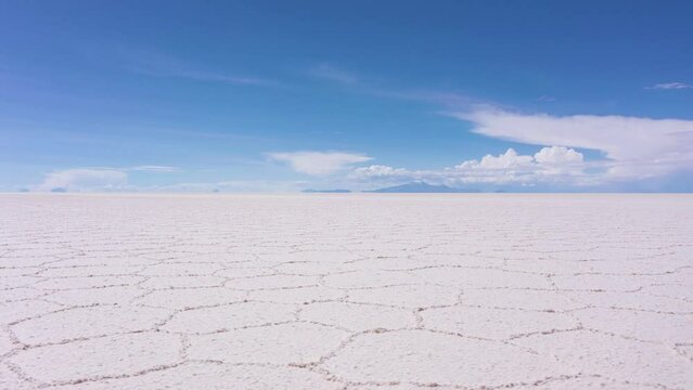 Uyuni Salt Flats on Sunny Day. Salar De Uyuni. Aerial View. Altiplano, Bolivia. Dry Season. Hexagonal Salt Formations and Crack Patterns. Drone Flies Sideways at Low Level. Wide Shot. Slider Shot