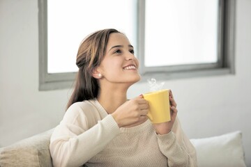 Woman holding yellow cup and looking up with smile in white background