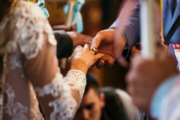 Closeup shot of groom putting the marriage ring in his bride's finger in the church