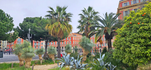 City views through plants in Jardin Albert 1er, in cloudy weather, façade from Place Massena is the central square of Nice, France