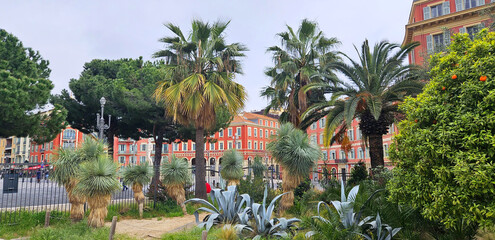 City views through plants in Jardin Albert 1er, in cloudy weather, façade from Place Massena is the central square of Nice, France