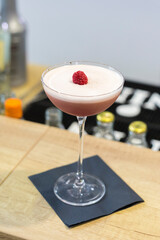 A beautiful cocktail garnished with raspberries.