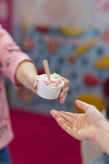 holds out his hand with ice cream. Give a paper cup of ice cream.