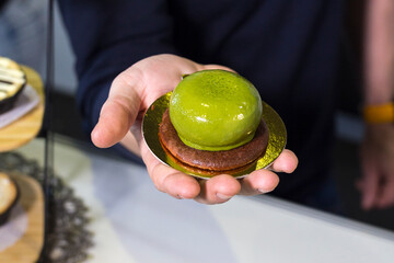 Round cake with green icing on hand