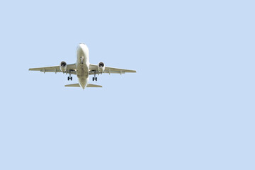 Passenger white airplane flying in the sky. Landing plane. View from below. Light blue colored in the background.