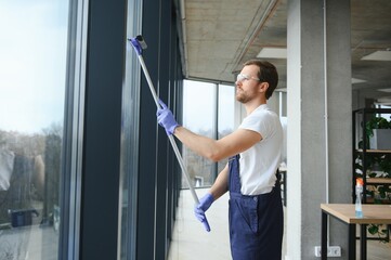 An employee of a professional cleaning service washes the glass of the windows of the building. Showcase cleaning for shops and businesses.