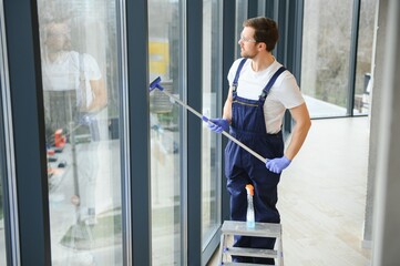 An employee of a professional cleaning service washes the glass of the windows of the building. Showcase cleaning for shops and businesses.