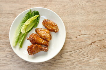crispy fried chicken drum stick and  wing dressing spicy Korean sauce and topping white sesame on plate 
