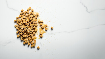 Brown sugar cubes on white marble background with copy space. Top view