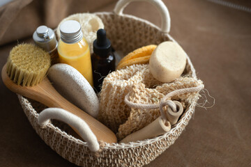 Obraz na płótnie Canvas woven basket with natural body care products - sponge, towel, loofah, soap, face brush and bottles